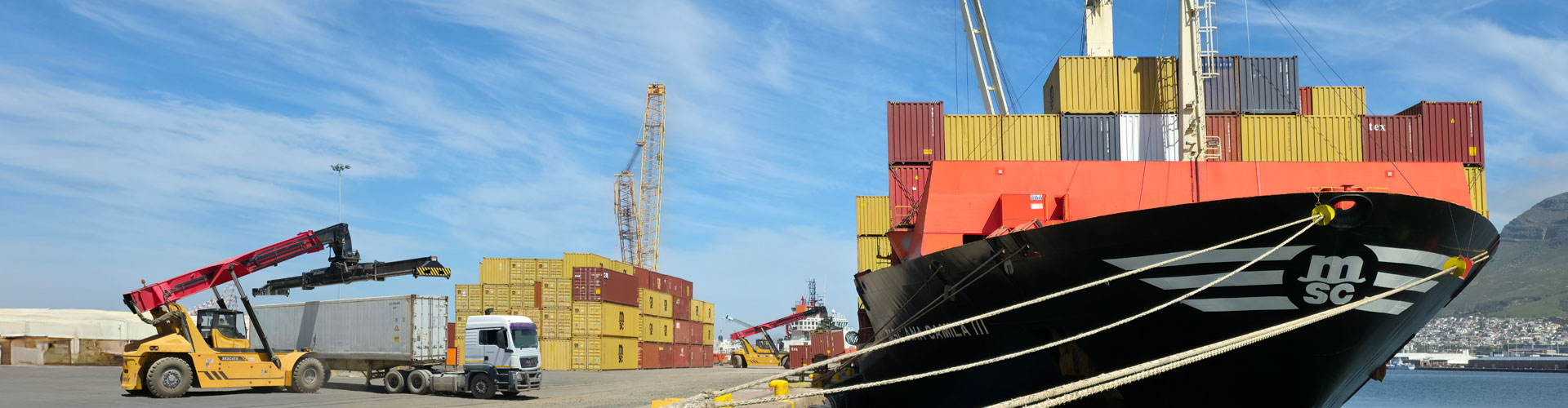 ship cargo with containers and reach stacker in the background